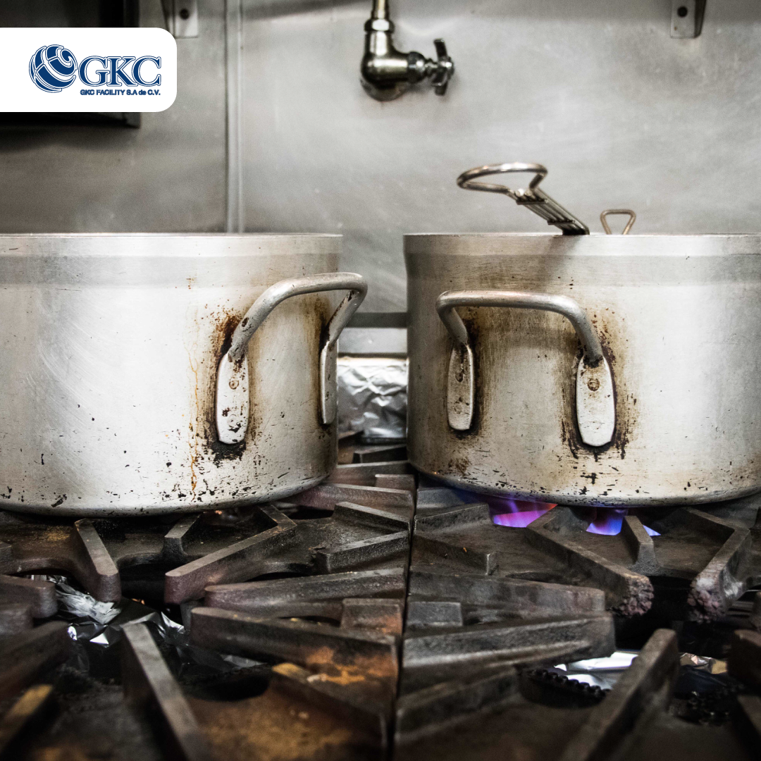 Ollas industriales con grasa acumulada sobre estufa de cocina profesional.